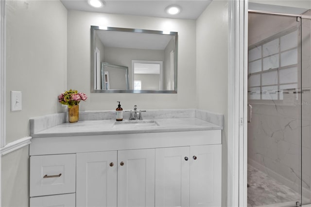 full bathroom with a marble finish shower and vanity