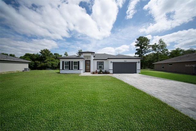 prairie-style home with driveway, stucco siding, an attached garage, and a front yard