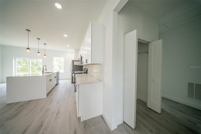 kitchen featuring white cabinets, light countertops, light wood-type flooring, and a sink