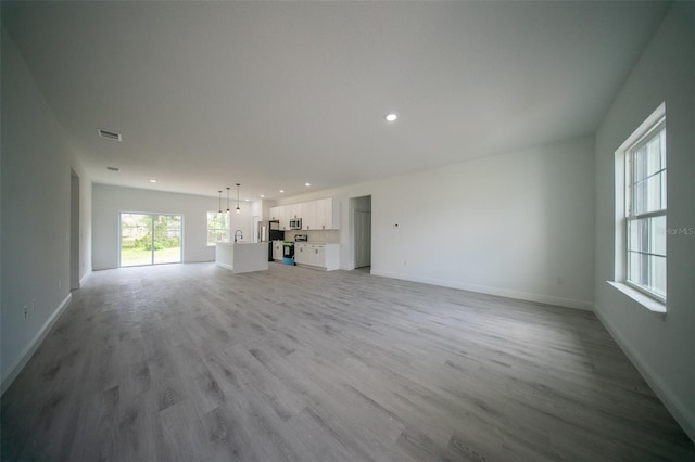unfurnished living room featuring light wood-style flooring, baseboards, and recessed lighting