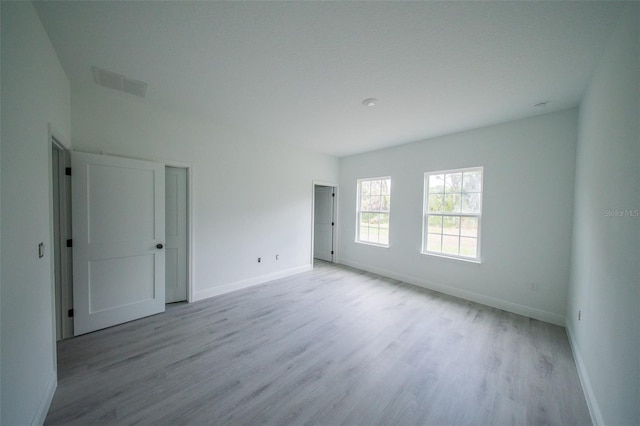 empty room with baseboards, light wood-style floors, and visible vents