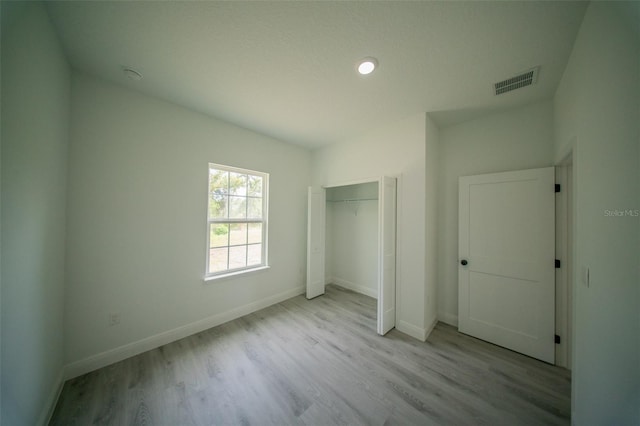 unfurnished bedroom featuring a closet, visible vents, wood finished floors, and baseboards