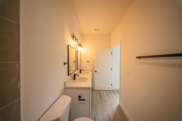 bathroom featuring toilet, wood finished floors, visible vents, baseboards, and vanity