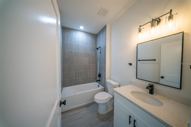 bathroom with toilet, visible vents, vanity, wood finished floors, and bathing tub / shower combination
