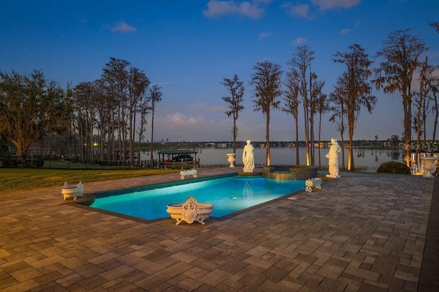 view of swimming pool with a patio area, a water view, fence, and a pool with connected hot tub