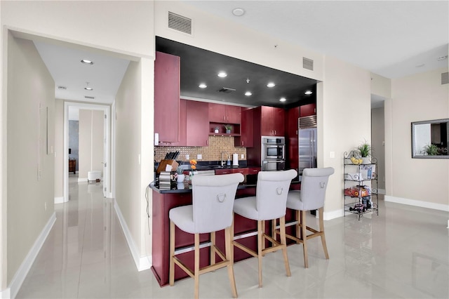 150 E Robinson St Unit 2002, Orlando, FL 32801 - kitchen featuring dark brown cabinets, decorative backsplash, stainless steel appliances, a peninsula, and dark countertops