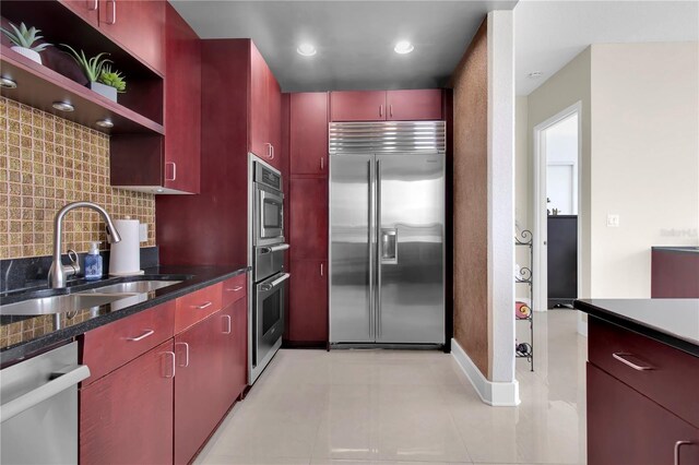 150 E Robinson St Unit 2002, Orlando, FL 32801 - kitchen featuring appliances with stainless steel finishes, a sink, backsplash, baseboards, and red cabinets