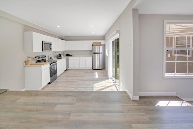2927 Ahern Dr, Orlando, FL 32817 - kitchen with a sink, stainless steel appliances, light wood-type flooring, white cabinetry, and light countertops