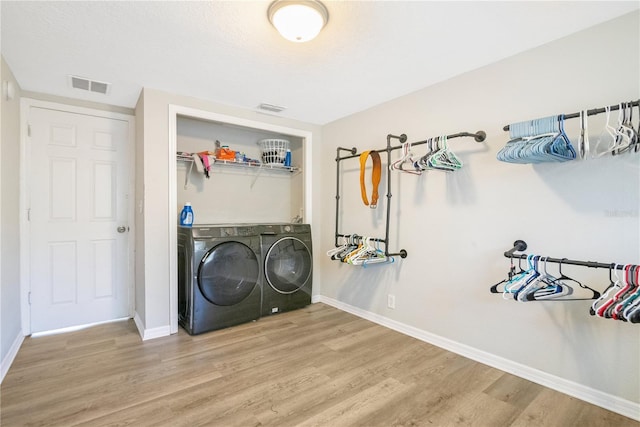 2927 Ahern Dr, Orlando, FL 32817 - clothes washing area with baseboards, visible vents, wood finished floors, washing machine and clothes dryer, and laundry area