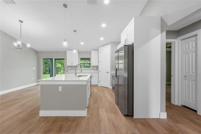 274 W Bolero Pl, Citrus Springs, FL 34434 - kitchen with stainless steel fridge, white cabinetry, light countertops, an island with sink, and light wood-style flooring