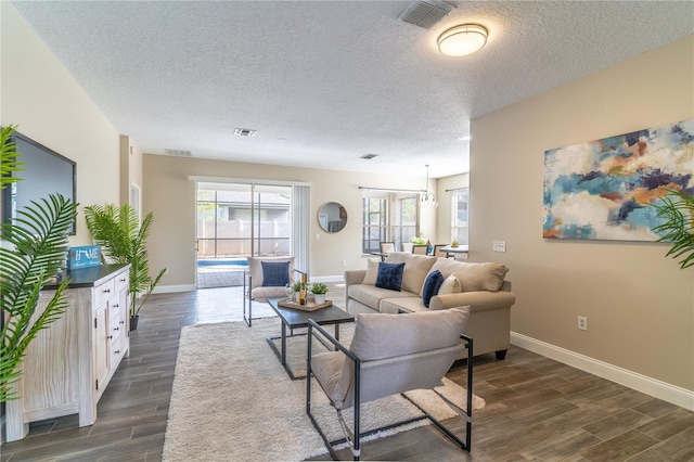 living area featuring a textured ceiling, visible vents, baseboards, and dark wood-type flooring