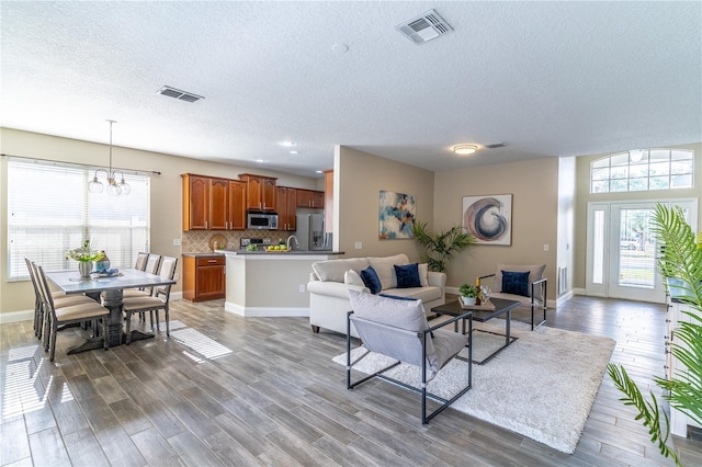 living area featuring light wood finished floors, a textured ceiling, and visible vents