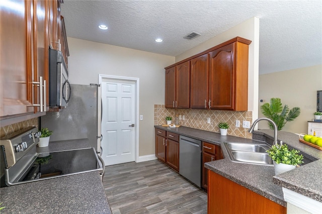 kitchen featuring a sink, dark countertops, visible vents, appliances with stainless steel finishes, and dark wood-style floors