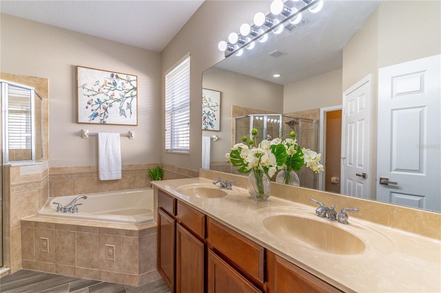 full bath featuring a sink, double vanity, a garden tub, and a shower stall