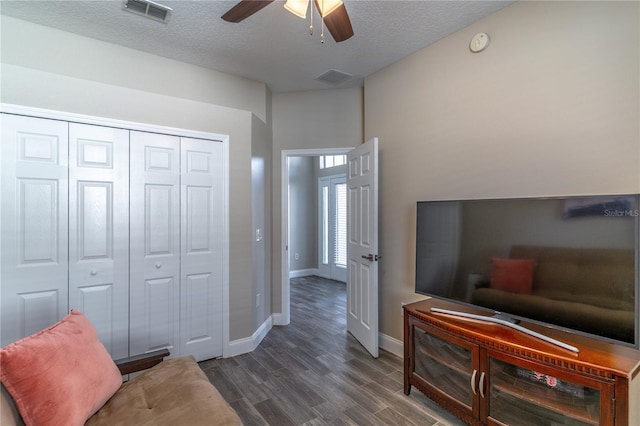 living area featuring dark wood finished floors, visible vents, baseboards, a textured ceiling, and ceiling fan