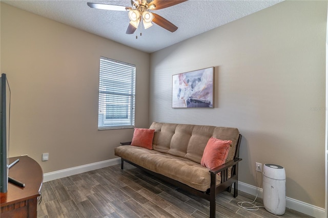 living area featuring a textured ceiling, baseboards, a ceiling fan, and dark wood-style floors