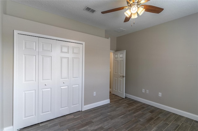 unfurnished bedroom with a closet, dark wood finished floors, visible vents, and baseboards