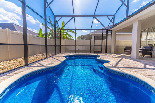 view of swimming pool with glass enclosure, a patio, a fenced in pool, and fence