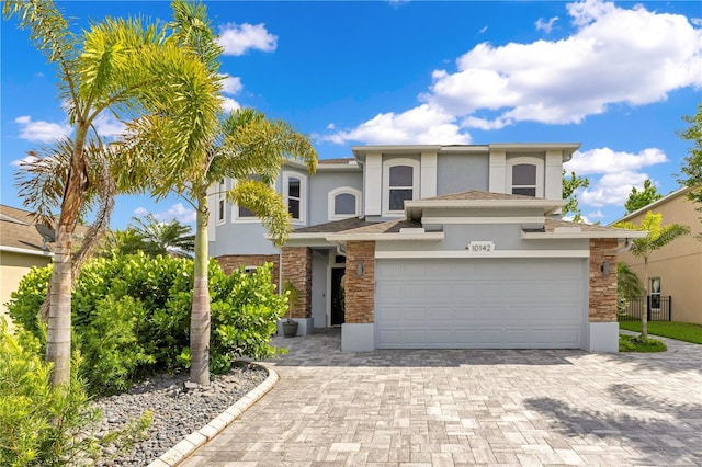 traditional home featuring stone siding, stucco siding, and decorative driveway