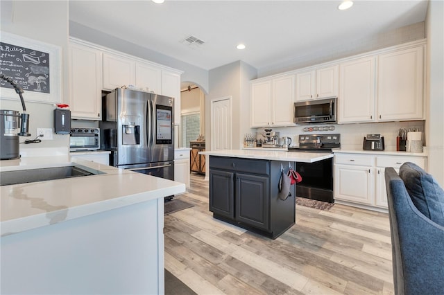 kitchen with stainless steel appliances, white cabinetry, arched walkways, and visible vents