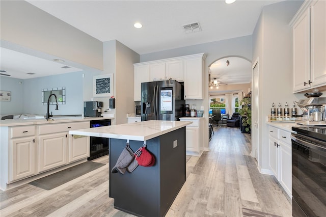 kitchen with a center island, beverage cooler, ceiling fan, visible vents, and black appliances