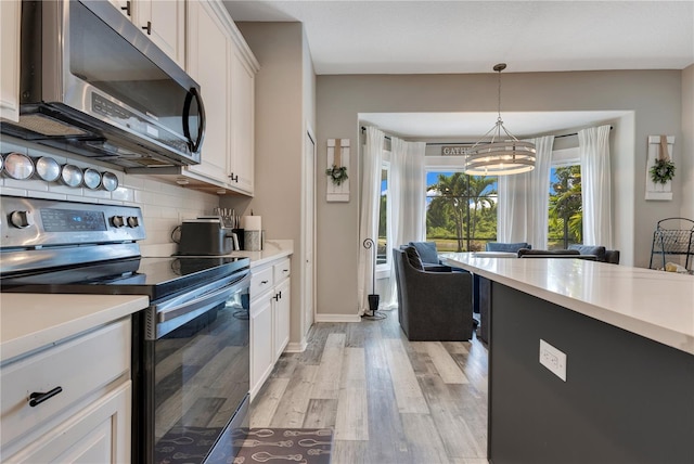 kitchen with decorative backsplash, white cabinetry, a notable chandelier, and appliances with stainless steel finishes