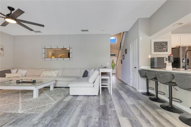 living area with baseboards, ceiling fan, visible vents, and wood finished floors