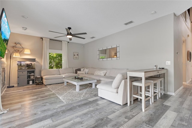 living area with a ceiling fan, visible vents, and wood finished floors