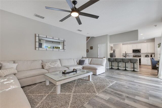 living room featuring ceiling fan, light wood-type flooring, visible vents, and recessed lighting
