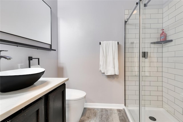 full bathroom featuring a stall shower, baseboards, toilet, vanity, and wood finished floors