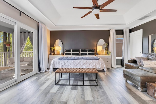 bedroom featuring a tray ceiling, visible vents, light wood finished floors, and access to exterior