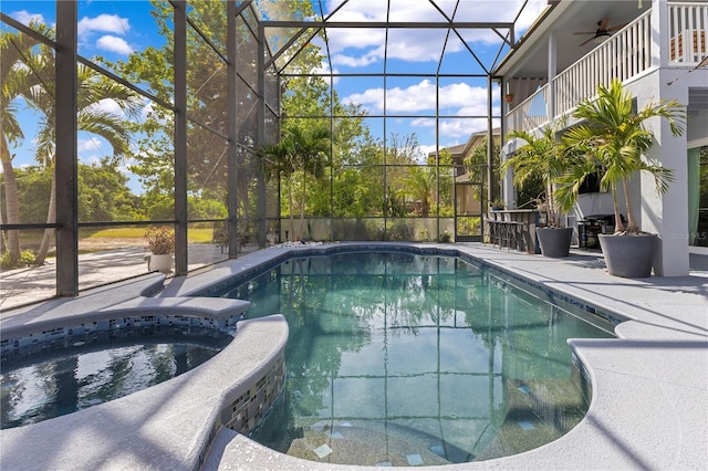 view of swimming pool with a ceiling fan, a patio area, glass enclosure, and a pool with connected hot tub