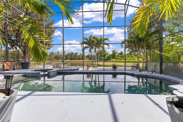 view of swimming pool featuring a patio area, glass enclosure, and a pool with connected hot tub