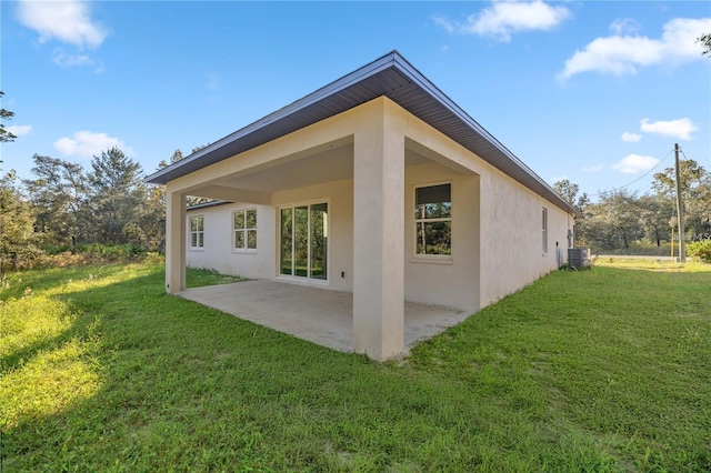 back of house featuring a yard, stucco siding, central AC unit, and a patio
