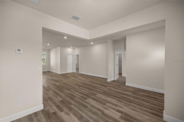 empty room with recessed lighting, baseboards, visible vents, and dark wood finished floors