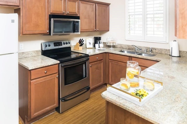 3643 Calabria Ave, Davenport, FL 33897 - kitchen with light stone countertops, light wood finished floors, a sink, brown cabinets, and stainless steel appliances