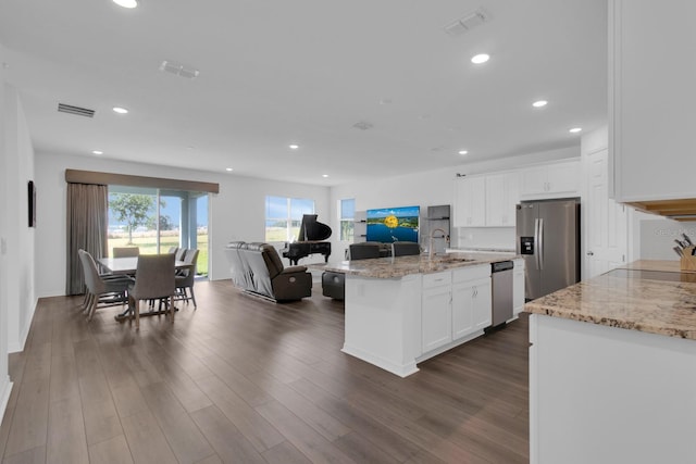 kitchen with stainless steel appliances, open floor plan, a sink, white cabinetry, and recessed lighting