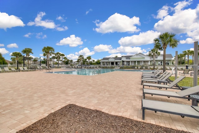 community pool with a patio and fence