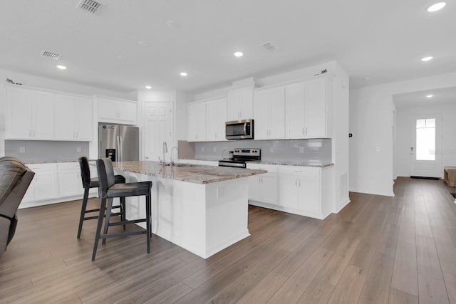 3017 Ambersweet Pl, Clermont, FL 34711 - kitchen featuring stainless steel appliances, a kitchen island with sink, recessed lighting, light stone counters, and a kitchen breakfast bar