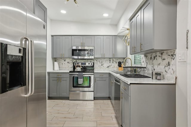318 E Jersey St, Orlando, FL 32806 - kitchen with appliances with stainless steel finishes, gray cabinetry, a sink, decorative backsplash, and recessed lighting