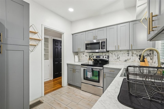 318 E Jersey St, Orlando, FL 32806 - kitchen featuring stainless steel appliances, gray cabinets, tasteful backsplash, light stone counters, and recessed lighting