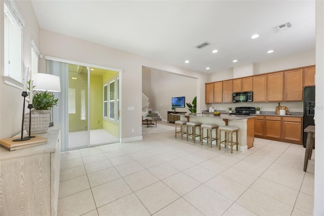 14244 Walcott Ave, Orlando, FL 32827 - kitchen with black appliances, recessed lighting, a center island with sink, a kitchen bar, and brown cabinetry