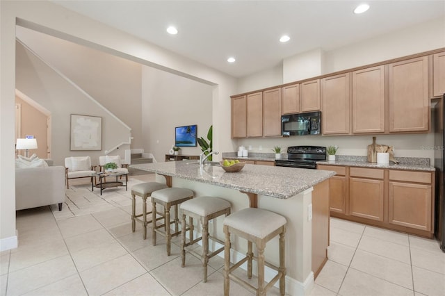 14244 Walcott Ave, Orlando, FL 32827 - kitchen with black appliances, light tile patterned floors, a center island with sink, light stone counters, and a breakfast bar area