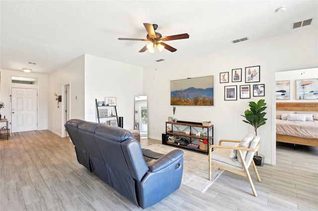 living area with light wood finished floors, a ceiling fan, and baseboards