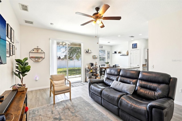 living area featuring ceiling fan, light wood finished floors, and baseboards