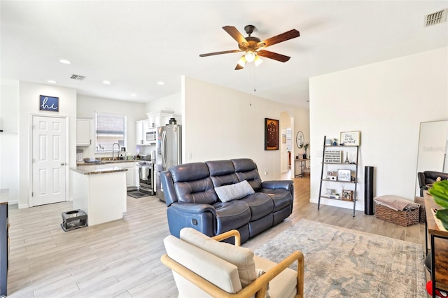 living room featuring a ceiling fan, light wood-type flooring, arched walkways, and recessed lighting