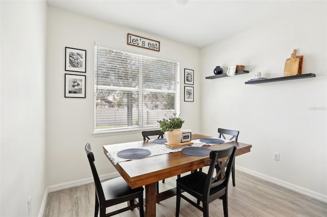 dining room featuring light wood finished floors, healthy amount of natural light, and baseboards