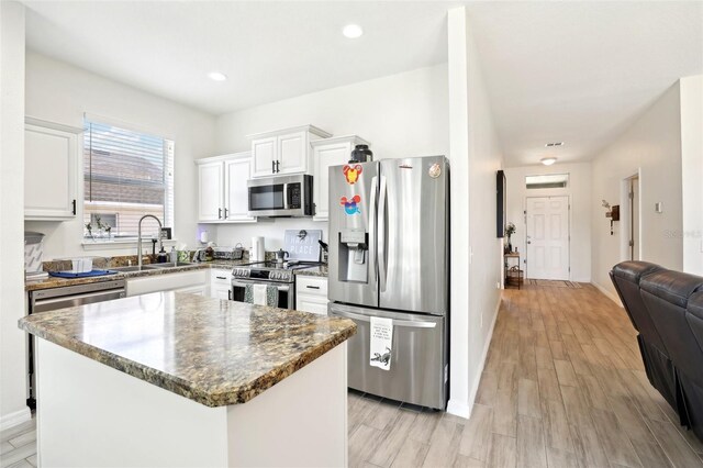kitchen with stainless steel appliances, a sink, white cabinets, baseboards, and recessed lighting