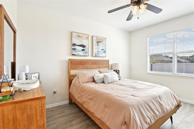 bedroom featuring baseboards, light wood-style floors, and ceiling fan