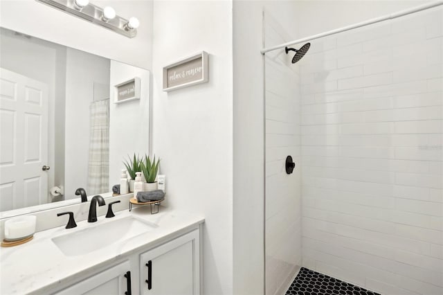 full bathroom featuring tiled shower and vanity